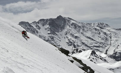 Unbekannter Skifahrer reitet auf Skiern auf einem schneebedeckten Berg, während er seinen Winterurlaub in den Schweizer Alpen an einem sonnigen Tag genießt - ADSF50597