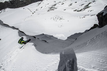 High angle view of unrecognizable skier in sport outwear riding skies on snowy mountain slope during sunny winter day on resort at Swiss Alps - ADSF50601