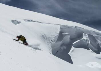 Anonymer Mann mit Skiern und Snowboard fährt über verschneites Land im Urlaub in den Schweizer Alpen - ADSF50604