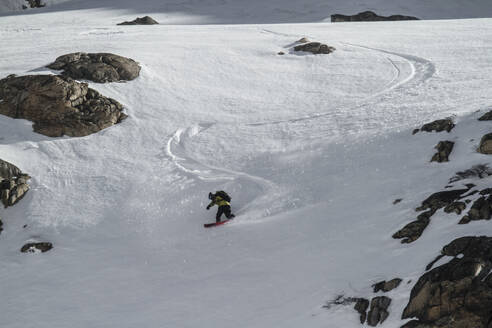 Ganzkörper Silhouette unerkennbar Person Reiten Snowboard auf Schnee bedeckten Landschaft während sonnigen Tag mit genießen Winterurlaub in den Schweizer Alpen - ADSF50628