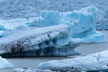Striking blue ice formations stand amidst the chilly waters in the majestic Vatnajokull National Park of Iceland, showcasing the raw beauty of nature. - ADSF50644
