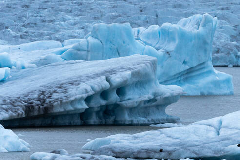 Im majestätischen Vatnajokull-Nationalpark in Island stehen auffallend blaue Eisformationen inmitten des kalten Wassers und zeigen die raue Schönheit der Natur. - ADSF50644