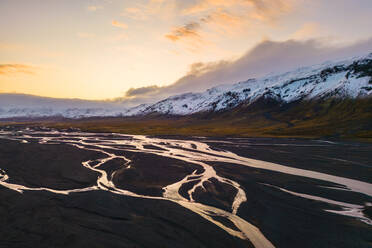 Luftaufnahme des Thorsmork-Tals mit sich schlängelnden Flüssen und schneebedeckten Bergen bei Sonnenuntergang im isländischen Hochland. - ADSF50659