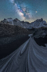 Ein herrlicher galaktischer Bogen zieht sich über verschneite Dünenpfade, die zu imposanten Berggipfeln führen - ADSF50668