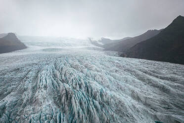 Expansive view of a glacier with rugged peaks at Vatnajokull National Park, under a dramatic cloudy sky. - ADSF50670