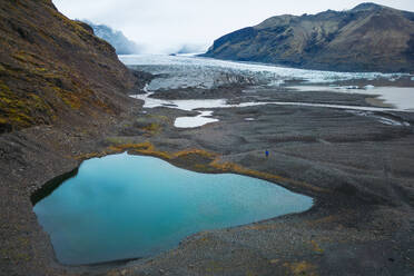 Tranquil blue waters of a glacier lagoon with Vatnajokull in the background under a cloudy sky. - ADSF50681
