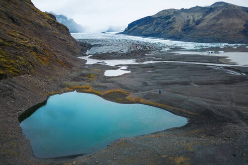 Ruhiges blaues Wasser einer Gletscherlagune mit dem Vatnajokull im Hintergrund unter einem bewölkten Himmel. - ADSF50681