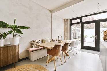 Esszimmer mit langem Holztisch und Stühlen an einem großen hellen Fenster in einer modernen Wohnung - ADSF50739