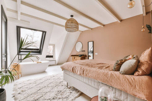 Interieur eines modernen, luxuriösen Schlafzimmers mit bequemem Bett und Badewanne in einer geräumigen Dachgeschosswohnung - ADSF50741