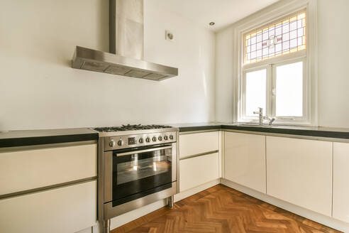 White cabinets and stainless steel oven and rangehood in modern kitchen with window at apartment - ADSF50752