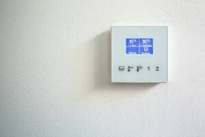 Nahaufnahme der Zahl auf dem Bildschirm eines intelligenten Thermostats an der weißen Wand eines luxuriösen Penthouses - ADSF50768
