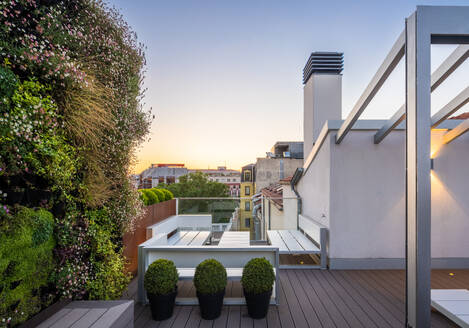 Couchtisch und Bänke auf dem Dach eines luxuriösen Penthouses mit Bäumen und Pflanzen gegen den klaren blauen Himmel - ADSF50773