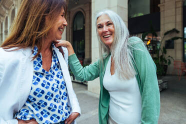 Beautiful senior women bonding outdoors in the city - Attractive cheerful mature female friends having fun, shopping and bonding, concepts about elderly lifestyle - DMDF07628