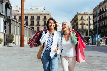 Schöne ältere Frauen, die sich in der Stadt im Freien treffen - Attraktive, fröhliche, reife Freundinnen, die Spaß haben, einkaufen gehen und sich austauschen, Konzepte für den älteren Lebensstil - DMDF07652