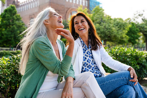 Schöne ältere Frauen, die sich in der Stadt im Freien treffen - Attraktive, fröhliche, reife Freundinnen, die Spaß haben, einkaufen gehen und sich austauschen, Konzepte für den älteren Lebensstil - DMDF07749