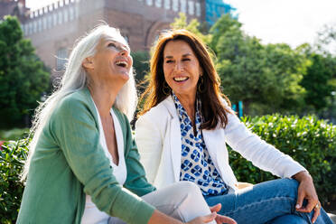 Beautiful senior women bonding outdoors in the city - Attractive cheerful mature female friends having fun, shopping and bonding, concepts about elderly lifestyle - DMDF07750