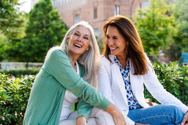 Beautiful senior women bonding outdoors in the city - Attractive cheerful mature female friends having fun, shopping and bonding, concepts about elderly lifestyle - DMDF07755