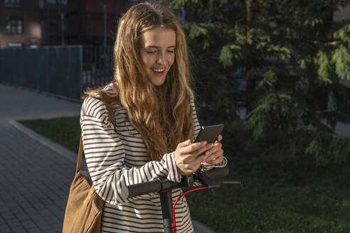 Lächelnde blonde Frau mit Textnachrichten auf einem Smartphone - VPIF09091