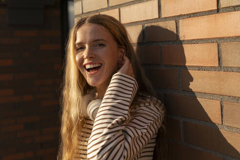 Happy blond woman in front of brick wall  - VPIF09149