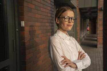 Businesswoman with arms crossed standing on footpath - VPIF09187