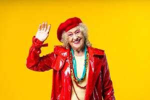 Schöne ältere alte Frau in schicken Partykleidern, die auf einem farbigen Hintergrund im Studio agiert - Konzeptbild über drittes Alter und Seniorität, alte Menschen, die sich innerlich jung fühlen. - DMDF07832