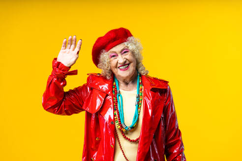 Beautiful senior old woman wearing fancy party clothes acting on a colored background in studio - Conceptual image about third age and seniority, old people feeling young inside. - DMDF07832