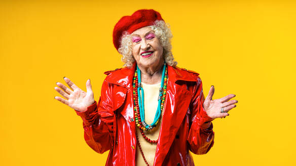 Beautiful senior old woman wearing fancy party clothes acting on a colored background in studio - Conceptual image about third age and seniority, old people feeling young inside. - DMDF07833