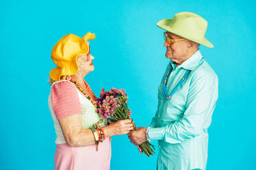 Schönes älteres altes Paar in schicker Partykleidung, das im Studio auf einem farbigen Hintergrund agiert. Konzeptbild über das dritte Lebensalter und das Alter, alte Menschen, die sich innerlich jung fühlen. - DMDF07867