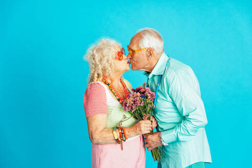 Schönes älteres altes Paar in schicker Partykleidung, das im Studio auf einem farbigen Hintergrund agiert. Konzeptbild über das dritte Lebensalter und das Alter, alte Menschen, die sich innerlich jung fühlen. - DMDF07869