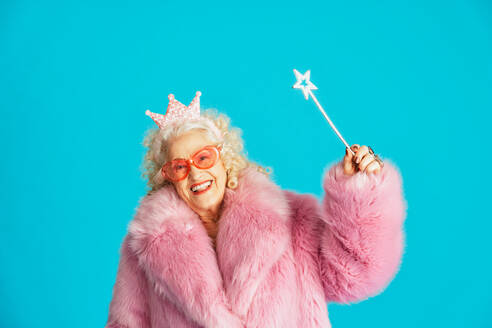 Schöne ältere alte Frau in schicken Partykleidern, die auf einem farbigen Hintergrund im Studio agiert - Konzeptbild über drittes Alter und Seniorität, alte Menschen, die sich innerlich jung fühlen. - DMDF07883
