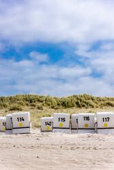 Deutschland, Schleswig-Holstein, Nummerierte Strandkörbe mit Kapuze auf der Insel Sylt - EGBF00989
