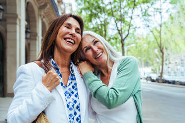 Schöne ältere Frauen, die sich in der Stadt im Freien treffen - Attraktive, fröhliche, reife Freundinnen, die Spaß haben, einkaufen gehen und sich austauschen, Konzepte für den älteren Lebensstil - DMDF07901