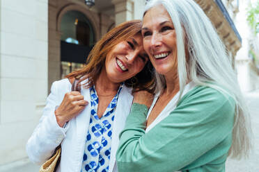 Schöne ältere Frauen, die sich in der Stadt im Freien treffen - Attraktive, fröhliche, reife Freundinnen, die Spaß haben, einkaufen gehen und sich austauschen, Konzepte für den älteren Lebensstil - DMDF07904