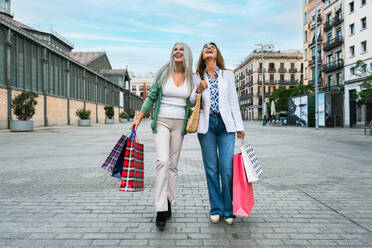 Schöne ältere Frauen, die sich in der Stadt im Freien treffen - Attraktive, fröhliche, reife Freundinnen, die Spaß haben, einkaufen gehen und sich austauschen, Konzepte für den älteren Lebensstil - DMDF07935