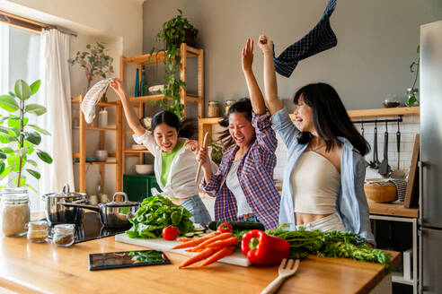 Happy beautiful chinese women friends bonding at home and cooking delicious meal together- Playful pretty asian female adults meeting and having fun at home, concepts about lifestyle, domestic life and friendship - DMDF07964