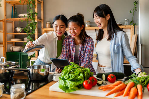 Happy beautiful chinese women friends bonding at home and cooking delicious meal together- Playful pretty asian female adults meeting and having fun at home, concepts about lifestyle, domestic life and friendship - DMDF07966