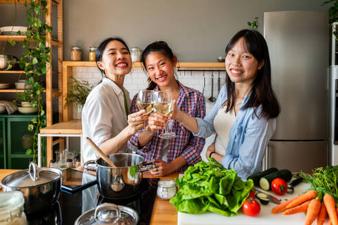 Happy beautiful chinese women friends bonding at home and cooking delicious meal together- Playful pretty asian female adults meeting and having fun at home, concepts about lifestyle, domestic life and friendship - DMDF07973