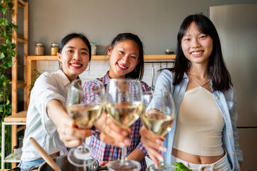 Glückliche, schöne chinesische Frauen, die sich zu Hause treffen und feiern und Wein trinken- Verspielte, hübsche asiatische Frauen, die sich zu Hause treffen und Spaß haben, Konzepte über Lebensstil, häusliches Leben und Freundschaft - DMDF07974