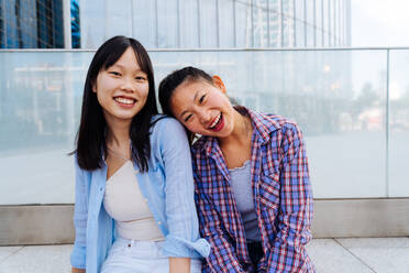 Happy beautiful chinese women friends bonding outdoors in the city - Playful pretty asian female adults meeting and having fun outside, concepts about lifestyle and friendship - DMDF08005