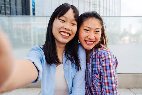 Happy beautiful chinese women friends bonding outdoors in the city - Playful pretty asian female adults meeting and having fun outside, concepts about lifestyle and friendship - DMDF08007