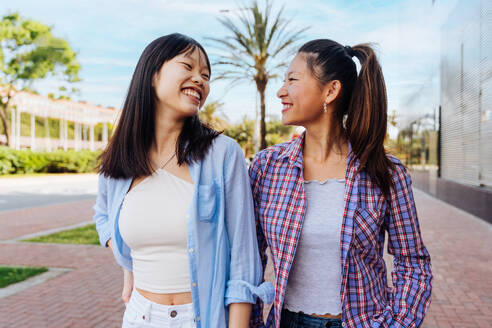 Happy beautiful chinese women friends bonding outdoors in the city - Playful pretty asian female adults meeting and having fun outside, concepts about lifestyle and friendship - DMDF08010