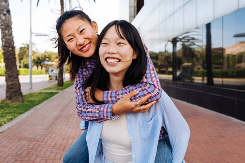 Happy beautiful chinese women friends bonding outdoors in the city - Playful pretty asian female adults meeting and having fun outside, concepts about lifestyle and friendship - DMDF08012