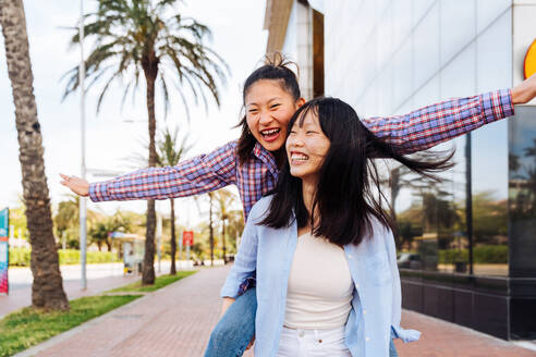 Happy beautiful chinese women friends bonding outdoors in the city - Playful pretty asian female adults meeting and having fun outside, concepts about lifestyle and friendship - DMDF08013