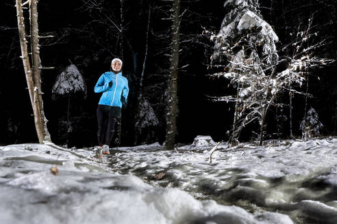 Junge Frau läuft nachts im Winterwald - STSF03804