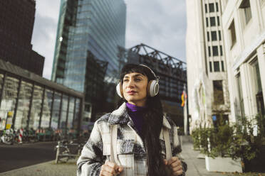 Frau hört Musik über Kopfhörer in der Stadt - JCCMF11003