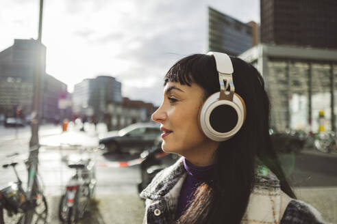 Frau hört Musik über drahtlose Kopfhörer in der Stadt - JCCMF11004