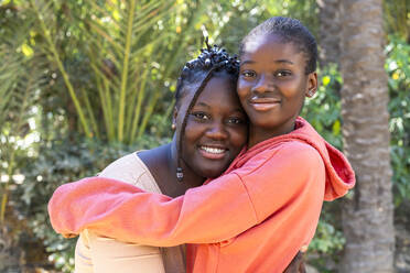 Happy friends embracing each other at park - DLTSF03726