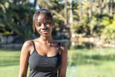 Lächelnde Frau mit schwarzem Tanktop im Park an einem sonnigen Tag - DLTSF03740