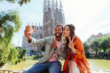 Multiracial beautiful happy couple of lovers dating at Sagrada Familia, Barcelona - Multiethnic tourists travelling in Europe and visiting a city in Spain, concepts about tourism and people lifestyle - DMDF08157