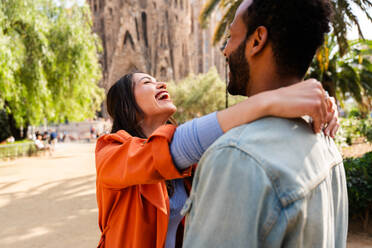 Multiracial beautiful happy couple of lovers dating at Sagrada Familia, Barcelona - Multiethnic tourists travelling in Europe and visiting a city in Spain, concepts about tourism and people lifestyle - DMDF08164